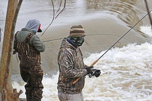 March 29, 2020 Fishing is still allowed under the stay at home order in Wisconsin. While the weather was windy and wet, and the water high, a group of fisherman on the Milwaukee River in Keltzsch Park in Glendale met a with some success fishing for steelhead or rainbow trout. Here fisherman on the bank fishing. Bandanas and balaclavas filled in for medical masks and kept the anglers warm as well. (Michael Sears/Milwaukee Journal-Sentinel via AP)