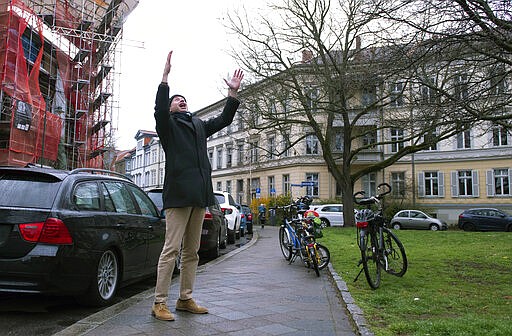 Silvius von Kessel, cathedral organist, choirmaster and composer of Erfurt Cathedral, conducts residents playing and singing 'By loving forces silently surrounded...' by Dietrich Bonhoeffer on their balconies and windows, as people practice social distancing due to coronavirus in Erfurt, central Germany, Sunday, March 29, 2020. For most people, the new coronavirus causes only mild or moderate symptoms, such as fever and cough. For some, especially older adults and people with existing health problems, it can cause more severe illness, including pneumonia. (AP Photo/Jens Meyer)