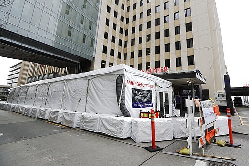 A new tent stands outside the emergency entrance of Harborview Medical Center Saturday, March 28, 2020, in Seattle. Harborview and University of Washington Medicine are preparing a &quot;surge plan&quot; that will enable its hospitals to better respond to the coronavirus outbreak. Under the plan, ambulatory patients with respiratory illness symptoms will be separated from other patients when they arrive at hospitals' emergency departments and be directed to a new treatment area in a tent outside of the emergency department. (AP Photo/Elaine Thompson)