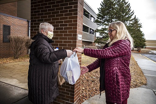 Patty Sagert, right, deliver some groceries Sunday, March 29, 2020, to her elderly mother, Janet Nemmers, who lives in a senior living community in Maplewood, Minn. Because of Sagert's ovarian cancer, Patty meets her outside the building and does not hug her out of fear of exposing her to Covid-19. (Richard Tsong-Taatarii/Star Tribune via AP)