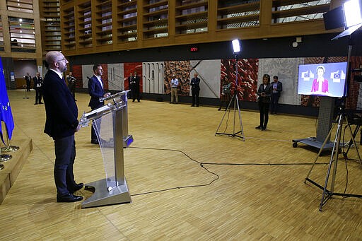 European Council President Charles Michel, left, speaks during a joint media conference with European Commission President Ursula von der Leyen, on screen right, after an EU summit by video conference in Brussels, Thursday, March 26, 2020. Following the informal video conference, members of the European Council adopted a statement on the EU actions in response to the COVID-19 outbreak. The new coronavirus causes mild or moderate symptoms for most people, but for some, especially older adults and people with existing health problems, it can cause more severe illness or death. (Francois Walschaerts, Pool Photo via AP)