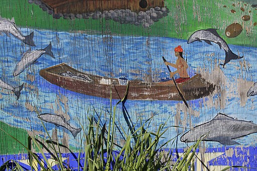 In this March 4, 2020, photo, a mural depicting traditional fishing methods used by the Karuk tribe to harvest salmon brightens the side of a food market in Orleans, Calif. A plan to demolish four dams on the lower Klamath River has sharpened a decades-old dispute over who has the biggest claim to the river's life-giving waters. The project, if it goes forward, would be the largest dam demolition project in U.S. history and reopen 400 stream miles of potential salmon habitat that's been blocked off for more than a century. Numerous tribes in southern Oregon and northern California, including the Karuk, are pushing for the dams' removal to save dwindling salmon populations in California's second-largest river. (AP Photo/Gillian Flaccus)
