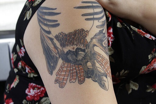 In this March 5, 2020, Georgiana Gensaw, a member of the Yurok Indian tribe, displays a tattoo of a fish hawk clutching a salmon in its talons that she had inked on her right bicep to honor her son, whose middle name is Ker-neet, the Yurok word for fish hawk, in Klamath, Calif. Gensaw, who lives where the Klamath River reaches the Pacific Ocean in Klamath. A plan to demolish four dams on the lower Klamath River has sharpened a decades-old dispute over who has the biggest claim to the river's life-giving waters. The project, if it goes forward, would be the largest dam demolition project in U.S. history and reopen 400 stream miles of potential salmon habitat that's been blocked off for more than a century. Numerous tribes in southern Oregon and northern California, including the Yurok, are pushing for the dams' removal to save dwindling salmon populations in California's second-largest river. (AP Photo/Gillian Flaccus)