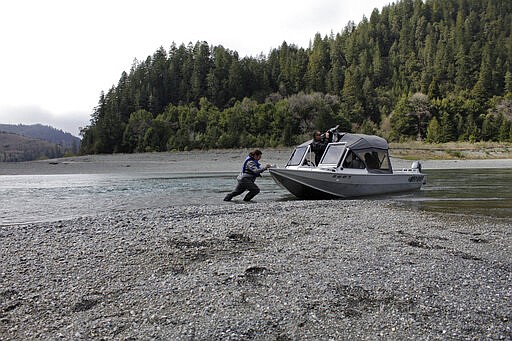 In this March 5, 2020, photo, Hunter Maltz, a fish technician for the Yurok tribe, pushes a jet boat into the Klamath River at the confluence of the Klamath River and Blue Creek as Keith Parker, a Yurok tribal fisheries biologist, watches near Klamath, Calif. A plan to demolish four dams on the lower Klamath River has sharpened a decades-old dispute over who has the biggest claim to the river's life-giving waters. The project, if it goes forward, would be the largest dam demolition project in U.S. history and reopen 400 stream miles of potential salmon habitat that's been blocked off for more than a century. Numerous tribes in southern Oregon and northern California, including the Yurok, are pushing for the dams' removal to save dwindling salmon populations in California's second-largest river. (AP Photo/Gillian Flaccus)