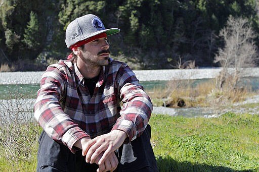 In this March 4, 2020, photo, Chook-Chook Hillman, a member of the Karuk tribe, sits along the banks of the Klamath River in Orleans, Calif. Hillman works to restore native salmon populations as part of his job with the Karuk's fisheries program and is fighting to remove four dams on the lower Klamath River to benefit dwindling numbers of salmon that are critical to the tribe's culture and diet. A plan to demolish the dams on California's second-largest river has sharpened a decades-old dispute over who has the biggest claim to the river's life-giving waters. The project, if it goes forward, would be the largest dam demolition project in U.S. history and reopen 400 stream miles of potential salmon habitat that's been blocked off for more than a century. (AP Photo/Gillian Flaccus)