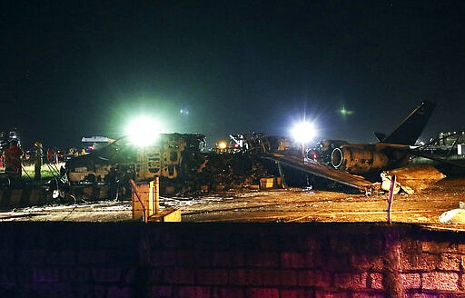 Firemen and rescuers stand beside the remains of a Lion Air, West Wind 24 aircraft after it caught fire during take off at Manila's International Airport in Philippines on Sunday, March 29, 2020. A plane carrying eight people has caught fire while attempting to take off from Manila's airport on a flight bound for Japan, killing all those on board, officials said. (AP Photo)