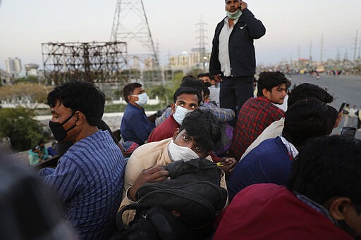 Indian migrant workers sit atop a bus, provided by the government, to travel to their villages following a lockdown amid concern over spread of coronavirus in New Delhi, India, Saturday, March 28, 2020. Authorities sent a fleet of buses to the outskirts of India's capital on Saturday to meet an exodus of migrant workers desperately trying to reach their home villages during the world's largest coronavirus lockdown. Thousands of people, mostly young male day laborers but also families, fled their New Delhi homes after Prime Minister Narendra Modi announced a 21-day lockdown that began on Wednesday and effectively put millions of Indians who live off daily earnings out of work. (AP Photo/Altaf Qadri)