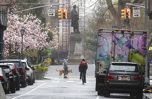 A cyclist and a dog walker are seen along West 16th Street near Union Square, Sunday, March 29, 2020, in New York. (AP Photo/Mary Altaffer)