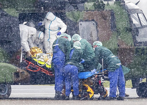 A coronavirus patient from Metz in France is transported from a military helicopter for treatment at the University Hospital in Essen, Germany, in bad weather Sunday March 29, 2020. Two COVID-19 coronavirus victims are to be treated in Germany. The COVID-19 coronavirus causes less serious symptoms for most people, but for some, especially older adults and people with existing health problems, it can cause severe illness and even death. (Marcel Kusch/dpa via AP)