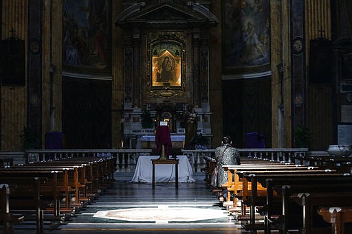 A woman prays at the Santa Maria ai Monti church, in Rome Sunday, March 29, 2020. The Vatican has told Catholic Churches around the world to move indoors the traditional outdoor Palm Sunday procession and service which re-enacts Christ&#146;s entrance into Jerusalem in the latest revision to Easter-time rituals given the coronavirus. The new coronavirus causes mild or moderate symptoms for most people, but for some, especially older adults and people with existing health problems, it can cause more severe illness or death. (Cecilia Fabiano/LaPresse via AP)