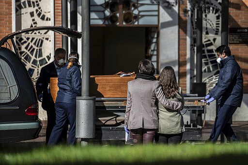 Relatives watch as the coffin containing the remains of a victim of the COVID-19 is taken for cremation at the Almudena cemetery in Madrid, Spain, Saturday March 28, 2020. In Spain, where stay-at-home restrictions have been in place for nearly two weeks, the official number of deaths is increasing daily. The new coronavirus causes mild or moderate symptoms for most people, but for some, especially older adults and people with existing health problems, it can cause more severe illness or death. (AP Photo/Olmo Calvo)