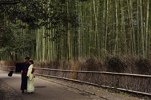 A couple takes a selfie at the Arashiyama Bamboo Forest in Kyoto, Japan, March 18, 2020. Widening travel restrictions and closures of most tourism and entertainment venues have gutted the tourism industry in many parts of the world, as well as in Japan.(AP Photo/Jae C. Hong)