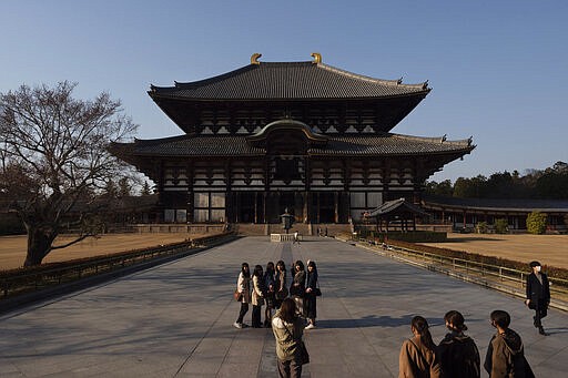 Tourists pause for photos in front of Todaiji temple's main hall in Nara, Japan, March 17, 2020. Nara was among the first Japanese town hit by the COVID-19 in late January, when a tour bus driver in town tested positive for the virus, becoming the first Japanese patient after carrying tourists from Wuhan, the epicenter of the pandemic. (AP Photo/Jae C. Hong)