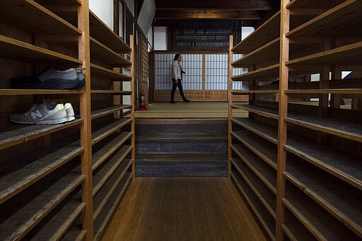 A tourist walks past shoe racks provided for visitors at Tenryuji Temple in the Arashiyama district of Kyoto, Japan, March 18, 2020. &quot;Arashiyama is empty,&quot; is a new catchphrase that appeared on posters in the area. &quot;It's time to visit Kyoto,&quot; they say, because there are no long lines and waiting to do river rafting, get into popular temples or cross the bridge. (AP Photo/Jae C. Hong)