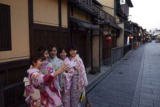 A group of Japanese women wearing kimono takes a selfie in the Gion district of Kyoto, Japan on March 18, 2020. Japanese tourism industry has taken a beating after Beijing banned group tours in late January. (AP Photo/Jae C. Hong)