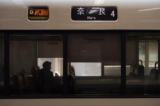 A man is silhouetted while sitting in a train bound for Nara at Kyoto Station in Kyoto, Japan on March 17, 2020. (AP Photo/Jae C. Hong)