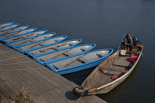 A ferryman sits in his boat while waiting for tourists in the Arashiyama district of Kyoto, Japan, March 18, 2020. (AP Photo/Jae C. Hong)