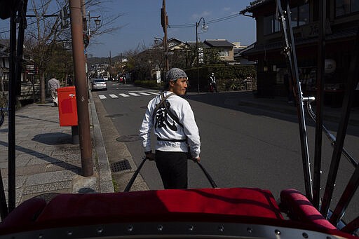 A rickshaw puller crosses the street in the Arashiyama district of Kyoto, Japan, March 18, 2020. (AP Photo/Jae C. Hong)