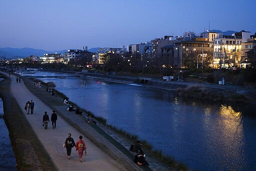 People stroll along the Kamo River in Kyoto, Japan, March 18, 2020. Kyoto's city government has an emergency fund for small to medium-size businesses who suffered sharp sales decline since the coronavirus outbreak. (AP Photo/Jae C. Hong)