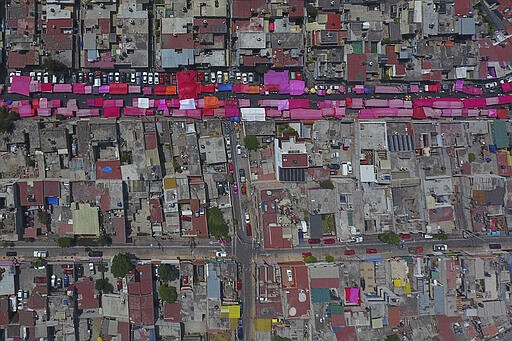 Stalls shielded from the sun with pink awnings line a road during a reduced, but still active weekly street market in northern Mexico City, Sunday, March 29, 2020, as many people stay home amid the spread of the new coronavirus. (AP Photo/Rebecca Blackwell)