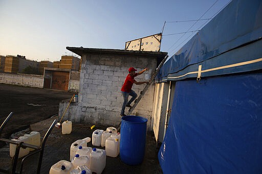 A man washes climbs to the roof of his restaurant to wash it with soap and water as a precautionary measure amid the spread of the new coronavirus in San Andres Mixquic, Mexico, Monday, March 30, 2020. (AP Photo/Fernando Llano)