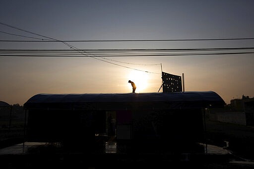 A man washes with soap and water the roof of his restaurant as a precautionary measure amid the spread of the new coronavirus in San Andres Mixquic, Mexico, Monday, March 30, 2020. (AP Photo/Fernando Llano)