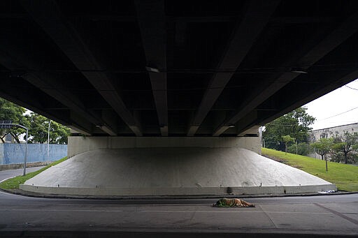 A homeless person sleeps under a highway near the Sambadrome, which is being equipped to shelter the homeless, as residents stay home in an attempt to contain the spread of the new coronavirus in Rio de Janeiro, Brazil, Monday, March 30, 2020. The new coronavirus causes mild or moderate symptoms for most people, but for some, especially older adults and people with existing health problems, it can cause more severe illness or death. (AP Photo/Leo Correa)