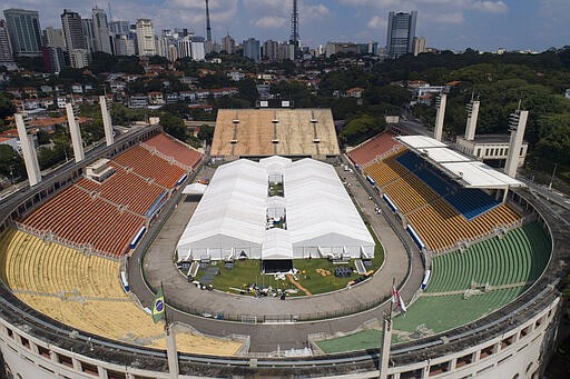 Workers set up a temporary field hospital to treat patients who have COVID-19 inside Pacaembu stadium in Sao Paulo, Brazil, Monday, March 30, 2020. The new coronavirus causes mild or moderate symptoms for most people, but for some, especially older adults and people with existing health problems, it can cause more severe illness or death.(AP Photo/Andre Penner)