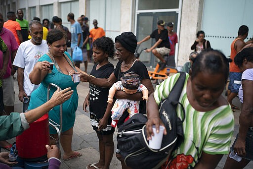 Homeless people gather for a free cup of coffee and bread from a private charity in downtown in Rio de Janeiro, Brazil, Monday, March 30, 2020, while most other residents are staying home to help contain the spread of the new coronavirus. (AP Photo/Leo Correa)