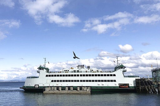 In this photo taken Sunday, March 29, 2020, a Washington state ferry docks at the Point Defiance Ferry Terminal in Tacoma, Wash., on the first day of a new reduced sailing schedule as part of the state's response to the new coronavirus, including cutting trips on the Seattle/Bainbridge and Seattle/Bremerton routes by about half. (AP Photo/Ted S. Warren)