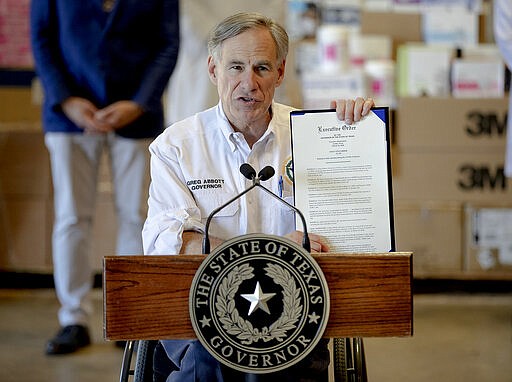 Texas Gov. Greg Abbott shows a new executive order regarding reporting data about the coronavirus during a news conference on Tuesday, March 24, 2020, in Austin, Texas. (Nick Wagner/Austin American-Statesman via AP)