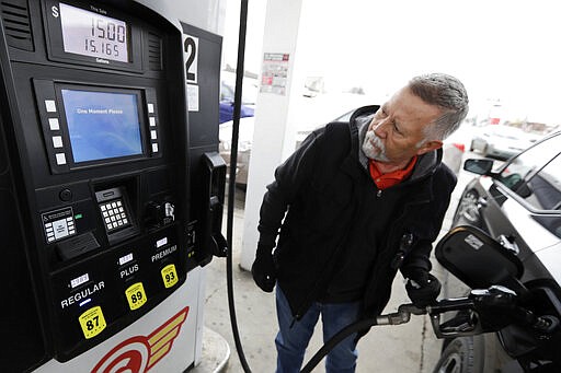 Julio DeJesus pumps gas for 98.9 cents a gallon, Monday, March 30, 2020, in Cleveland. Oil started the year above $60 and has plunged on expectations that a weakened economy will burn less fuel. The world is awash in oil, meanwhile, as producers continue to pull more of it out of the ground. (AP Photo/Tony Dejak)