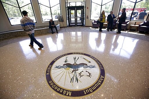 FILE - In this May 29, 2014, file photo, people stand in the lobby of the newly constructed Mashpee Wampanoag Tribe's Community Government Center in Mashpee, Mass., on Cape Cod. Tribe Chairman Cedric Cromwell announced in a post on the tribe's website on Friday, March 27, 2020, that he federal Bureau of Indian Affairs told them that the tribe's reservation will be &quot;disestablished&quot; and its land taken out of trust, per an order from Secretary of the Interior David Bernhardt. (AP Photo/Stephan Savoia, File)