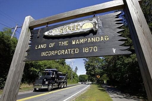 FILE - In this June 25, 2018, photo, a wooden sign advises motorists of the location of Mashpee Wampanoag Tribal lands in Massachusetts. Tribe Chairman Cedric Cromwell announced in a post on the tribe's website on Friday, March 27, 2020, that he federal Bureau of Indian Affairs told them that the tribe's reservation will be &quot;disestablished&quot; and its land taken out of trust, per an order from Secretary of the Interior David Bernhardt. (AP Photo/Steven Senne, File)