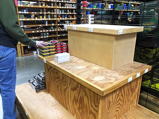 This image taken March 14, 2020, shows a nearly empty display shelf for ammunition at the Sportsmen's Warehouse in Meridian, Idaho. A sign at the store alerted customers that the store was limiting the number of firearms and ammunition that people could buy in a given day. (AP Photo/Lisa Marie Pane)