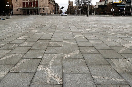 In this March 26, 2020, photo, Serbian police car patrols on an empty main square during a curfew set up to help prevent the spread of the new coronavirus in Belgrade, Serbia. Since declaring nationwide state of emergency Serbian President Aleksandar Vucic has suspended parliament, giving him widespread powers such as closing borders and introducing a 12-hour curfew. (AP Photo/Darko Vojinovic)