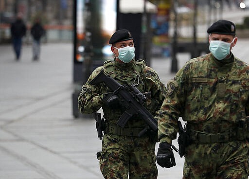 In this March 26, 2020, photo, Serbian army soldiers patrol in Belgrade's main pedestrian street, in Serbia. Since declaring nationwide state of emergency Serbian President Aleksandar Vucic has suspended parliament, giving him widespread powers such as closing borders and introducing a 12-hour curfew. (AP Photo/Darko Vojinovic)