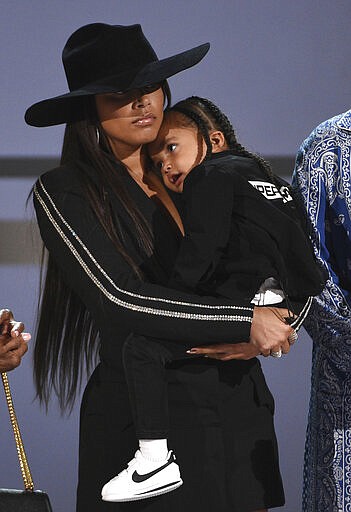 FILE - This June 23, 2019 file photo shows Lauren London, Nipsey Hussle's partner, and their son Kross on stage as the late rapper is presented with the humanitarian award at the BET Awards in Los Angeles. Hussle, 33, was shot and killed outside his Los Angeles clothing store on March 31, 2019. A year after Hussle's death, his popularity and influence are as strong as ever. He won two posthumous Grammys in January, he remains a favorite of his hip-hop peers and his death has reshaped his hometown of Los Angeles in some unexpected ways. (Photo by Chris Pizzello/Invision/AP, File)