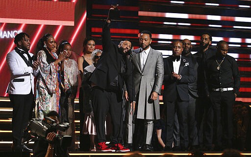 FILE - This Jan. 26, 2020 file photo shows DJ Khaled, center left, and John Legend, center right, and members of Nipsey Hussle's family accepting the award for best rap/sung performance at the 62nd annual Grammy Awards in Los Angeles. Hussle, 33, was shot and killed outside his Los Angeles clothing store on March 31, 2019. A year after Hussle's death, his popularity and influence are as strong as ever. He won two posthumous Grammys in January, he remains a favorite of his hip-hop peers and his death has reshaped his hometown of Los Angeles in some unexpected ways. (Photo by Matt Sayles/Invision/AP, File)