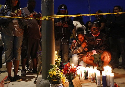 FILE - This March 31, 2019 file photo shows Haitian-French actor Jimmy Jean-Louis and his daughter Jasmin, 16, at a makeshift memorial for rapper Nipsey Hussle in Los Angeles. Hussle, 33, was shot and killed outside his Los Angeles clothing store in Los Angeles on March 31, 2019. A year after Hussle's death, his popularity and influence are as strong as ever. He won two posthumous Grammys in January, he remains a favorite of his hip-hop peers and his death has reshaped his hometown of Los Angeles in some unexpected ways. (AP Photo/Damian Dovarganes, File)