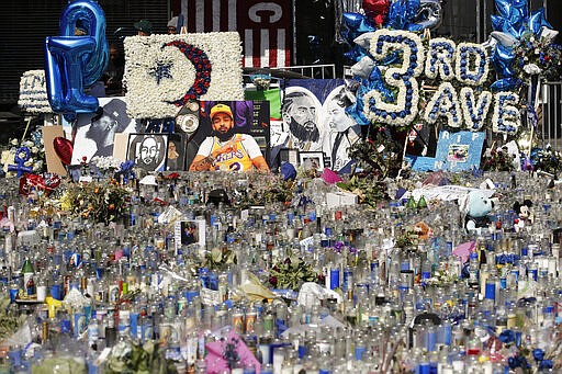 FILE - In thie April 11, 2019 file photo, a makeshift memorial site for slain rapper Nipsey Hussle is filled with candles outside The Marathon Clothing store in Los Angeles.  Hussle, 33, was shot and killed outside his Los Angeles clothing store in Los Angeles on March 31, 2019. A year after Hussle's death, his popularity and influence are as strong as ever. He won two posthumous Grammys in January, he remains a favorite of his hip-hop peers and his death has reshaped his hometown of Los Angeles in some unexpected ways. (AP Photo/Jae C. Hong, File)