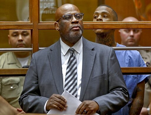 FILE - In this April 4, 2019, file photo, defense attorney Christopher Darden stands with Eric Holder, the suspect in the killing of rapper Nipsey Hussle, in a Los Angeles arraignment court. Hussle, 33, was shot and killed outside his Los Angeles clothing store in Los Angeles on March 31, 2019. A year after Hussle's death, his popularity and influence are as strong as ever. He won two posthumous Grammys in January, he remains a favorite of his hip-hop peers and his death has reshaped his hometown of Los Angeles in some unexpected ways. (AP Photo/Damian Dovarganes, Pool, File)