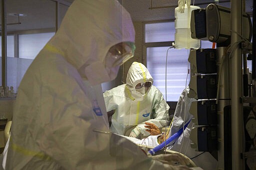 In this photo taken on Friday, March 27, 2020, healthcare workers assist a patience at one of the intensive care units (ICU) at German Trias i Pujol hospital in Badalona, in the Barcelona province, Spain. The new coronavirus causes mild or moderate symptoms for most people, but for some, especially older adults and people with existing health problems, it can cause more severe illness or death. (AP Photo/Anna Surinyach)