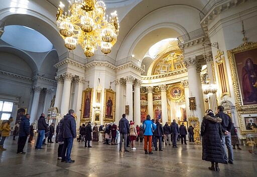 Orthodox believers gather for Sunday's prayer in the Holy Trinity Izmailovsky Cathedral in St.Petersburg, Russia, Sunday, March 29, 2020. The leader of the Russian Orthodox Church is calling on believers to stay away from churches during the coronavirus pandemic and to pray at home instead. The new coronavirus causes mild or moderate symptoms for most people, but for some, especially older adults and people with existing health problems, it can cause more severe illness or death. (AP Photo/Dmitri Lovetsky)