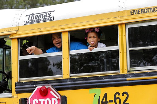 A congregant in a church bus yells out to news media as they leave services at the Life Tabernacle Church in Central, La., Sunday, March 29, 2020. Pastor Tony Spell has defied a shelter-in-place order by Louisiana Gov. John Bel Edwards, due to the new coronavirus pandemic, and continues to hold church services with hundreds of congregants. (AP Photo/Gerald Herbert)