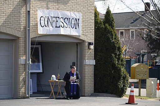 Father Bryce Evans waits to hear confession at the drive-up confession site of St. Maron's Maronite Catholic Church in northeast Minneapolis Monday, March 30, 2020 as efforts continue in Minnesota to slow down the coronavirus in the state. The new coronavirus causes mild or moderate symptoms for most people, but for some, especially older adults and people with existing health problems, it can cause more severe illness or death. (AP Photo/Jim Mone)