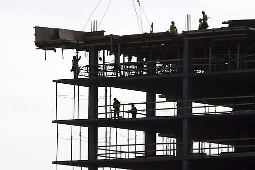 Work continues on a construction project Monday, March 30, 2020, in Minneapolis. An executive stay at home order was issued by Minnesota Gov. Tim Walz for non-essential businesses in an effort to slow down the coronavirus in the state. The new coronavirus causes mild or moderate symptoms for most people, but for some, especially older adults and people with existing health problems, it can cause more severe illness or death. (AP Photo/Jim Mone)