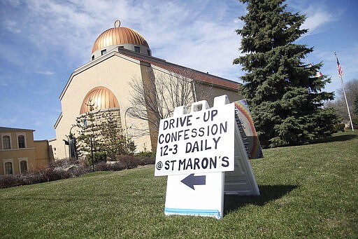 A sign outside St. Maron's Maronite Catholic Church in northeast Minneapolis posts the way to the drive-up confession site Monday, March 30, 2020 as efforts continue to slow down the coronavirus in the state. The new coronavirus causes mild or moderate symptoms for most people, but for some, especially older adults and people with existing health problems, it can cause more severe illness or death. (AP Photo/Jim Mone)