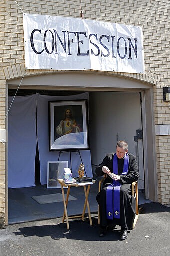 Father Bryce Evans waits to hear confession at the drive-up confession site of St. Maron's Maronite Catholic Church in northeast Minneapolis Monday, March 30, 2020 as efforts continue to slow down the coronavirus in the state. Priests in the northeast part of the city rotate at the confessional. The new coronavirus causes mild or moderate symptoms for most people, but for some, especially older adults and people with existing health problems, it can cause more severe illness or death. (AP Photo/Jim Mone)