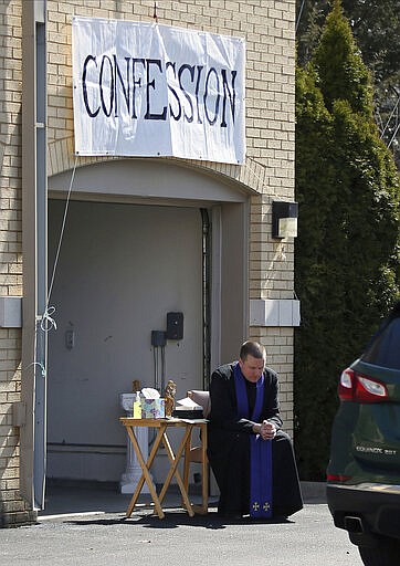 Father Bryce Evans hears confession at the drive-up confession site of St. Maron's Maronite Catholic Church in northeast Minneapolis Monday, March 30, 2020 as efforts continue in Minnesota to slow down the coronavirus in the state. The new coronavirus causes mild or moderate symptoms for most people, but for some, especially older adults and people with existing health problems, it can cause more severe illness or death. (AP Photo/Jim Mone)